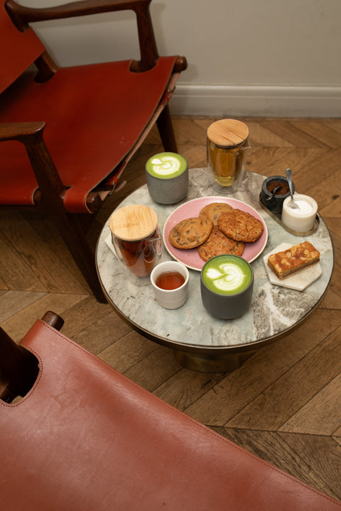 A coffee shop table with specialty tea, matcha latte, and pastries