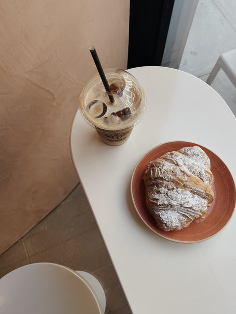 Iced coffee with croissant on a white table
